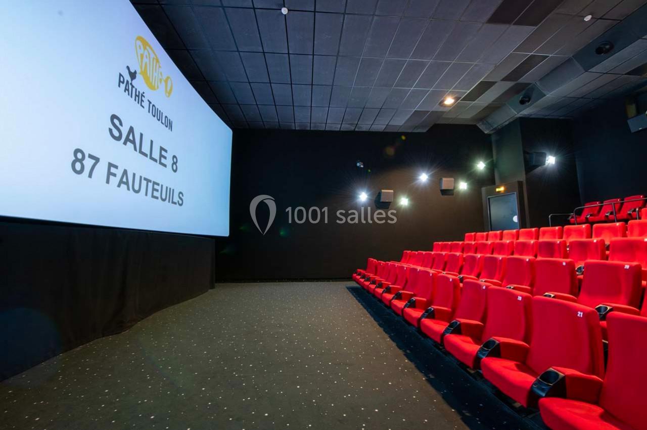 Salle de cinéma avec des sièges rouges alignés et un écran affichant ’Pathé Toulon, Salle 8, 87 fauteuils’.
