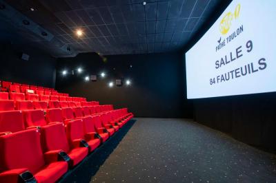 Salle colorée avec moquette violette et orange, plafond circulaire rouge, chaises modernes et affiches murales.