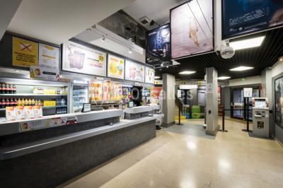 Salle de cinéma vide avec rangées de sièges rouges alignés et éclairage tamisé.