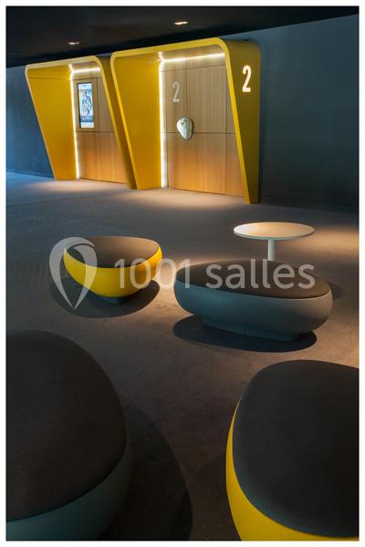 Fauteuils modernes et table basse dans un espace d'attente devant des portes numérotées au design contemporain.