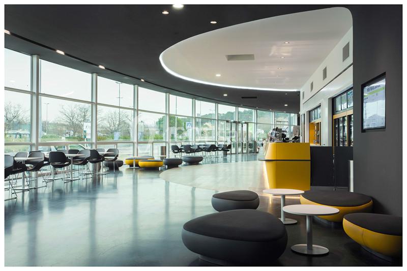 Intérieur d'un espace moderne avec mobilier design, grandes baies vitrées et comptoir d'accueil lumineux.