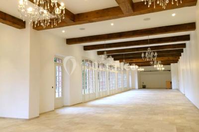 Statue blanche en forme de figure humaine tenant une vasque d'où s'écoule de l'eau, entourée de végétation.