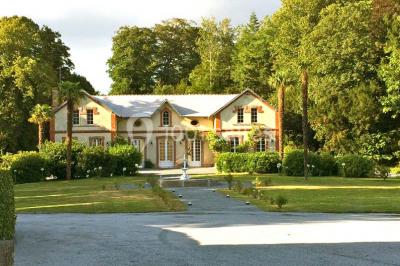 Statue blanche en forme de figure humaine tenant une vasque d'où s'écoule de l'eau, entourée de végétation.