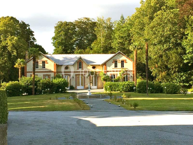 Grande maison de style traditionnel entourée d'un jardin verdoyant avec une allée centrale en gravier.