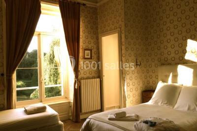 Statue blanche en forme de figure humaine tenant une vasque d'où s'écoule de l'eau, entourée de végétation.