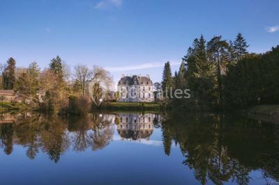 Statue blanche en forme de figure humaine tenant une vasque d'où s'écoule de l'eau, entourée de végétation.