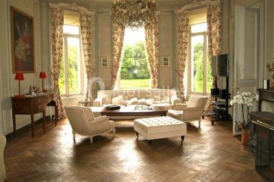 Statue blanche en forme de figure humaine tenant une vasque d'où s'écoule de l'eau, entourée de végétation.