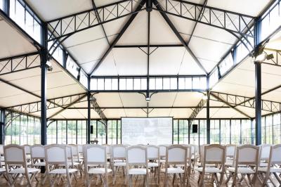 Chambre lumineuse avec lit double, bureau en bois, lampes allumées et rideaux à carreaux devant des fenêtres.