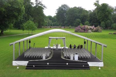 Chambre lumineuse avec lit double, bureau en bois, lampes allumées et rideaux à carreaux devant des fenêtres.