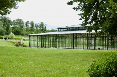 Chambre lumineuse avec lit double, bureau en bois, lampes allumées et rideaux à carreaux devant des fenêtres.