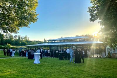 Chambre lumineuse avec lit double, bureau en bois, lampes allumées et rideaux à carreaux devant des fenêtres.
