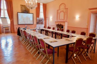 Chambre lumineuse avec lit double, bureau en bois, lampes allumées et rideaux à carreaux devant des fenêtres.