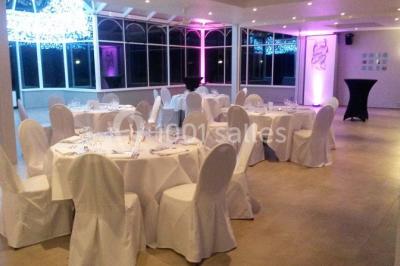 Jardin verdoyant avec pelouse, parterres fleuris, lampadaires verts et haies, entouré d'arbres sous un ciel dégagé.