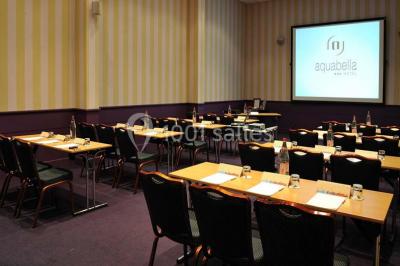 Lit double avec oreillers et coussins jaunes, éclairé par des lampes dorées, devant un mur décoré de motifs artistiques.