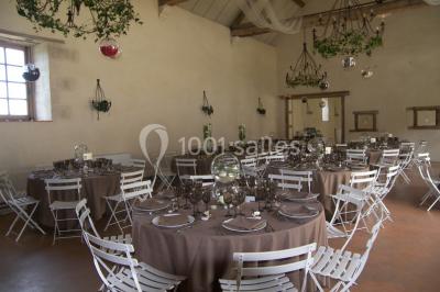 Salle lumineuse avec cuisine ouverte, murs rouges, poutres apparentes, mobilier en bois et fauteuils en osier.