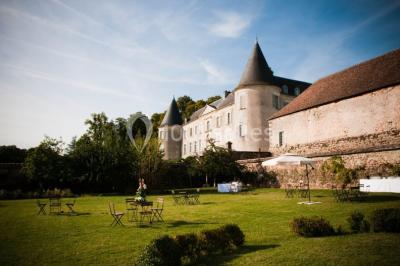 Salle lumineuse avec cuisine ouverte, murs rouges, poutres apparentes, mobilier en bois et fauteuils en osier.