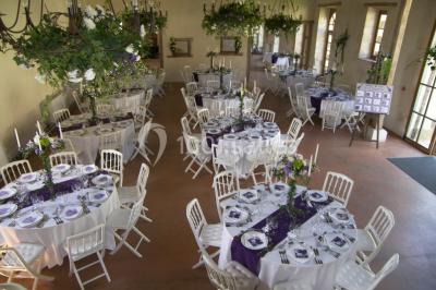 Salle lumineuse avec cuisine ouverte, murs rouges, poutres apparentes, mobilier en bois et fauteuils en osier.