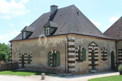 Salle lumineuse avec cuisine ouverte, murs rouges, poutres apparentes, mobilier en bois et fauteuils en osier.