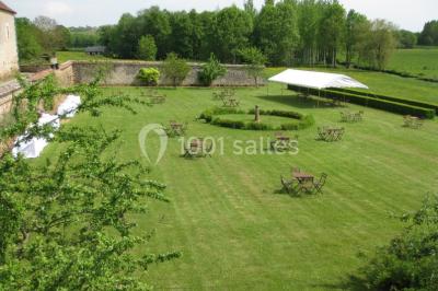 Salle lumineuse avec cuisine ouverte, murs rouges, poutres apparentes, mobilier en bois et fauteuils en osier.