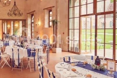 Salle lumineuse avec cuisine ouverte, murs rouges, poutres apparentes, mobilier en bois et fauteuils en osier.