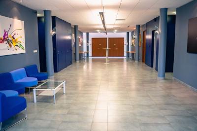 Un hall moderne avec des murs bleus, des fauteuils bleus, une table basse en verre et des œuvres d'art accrochées.