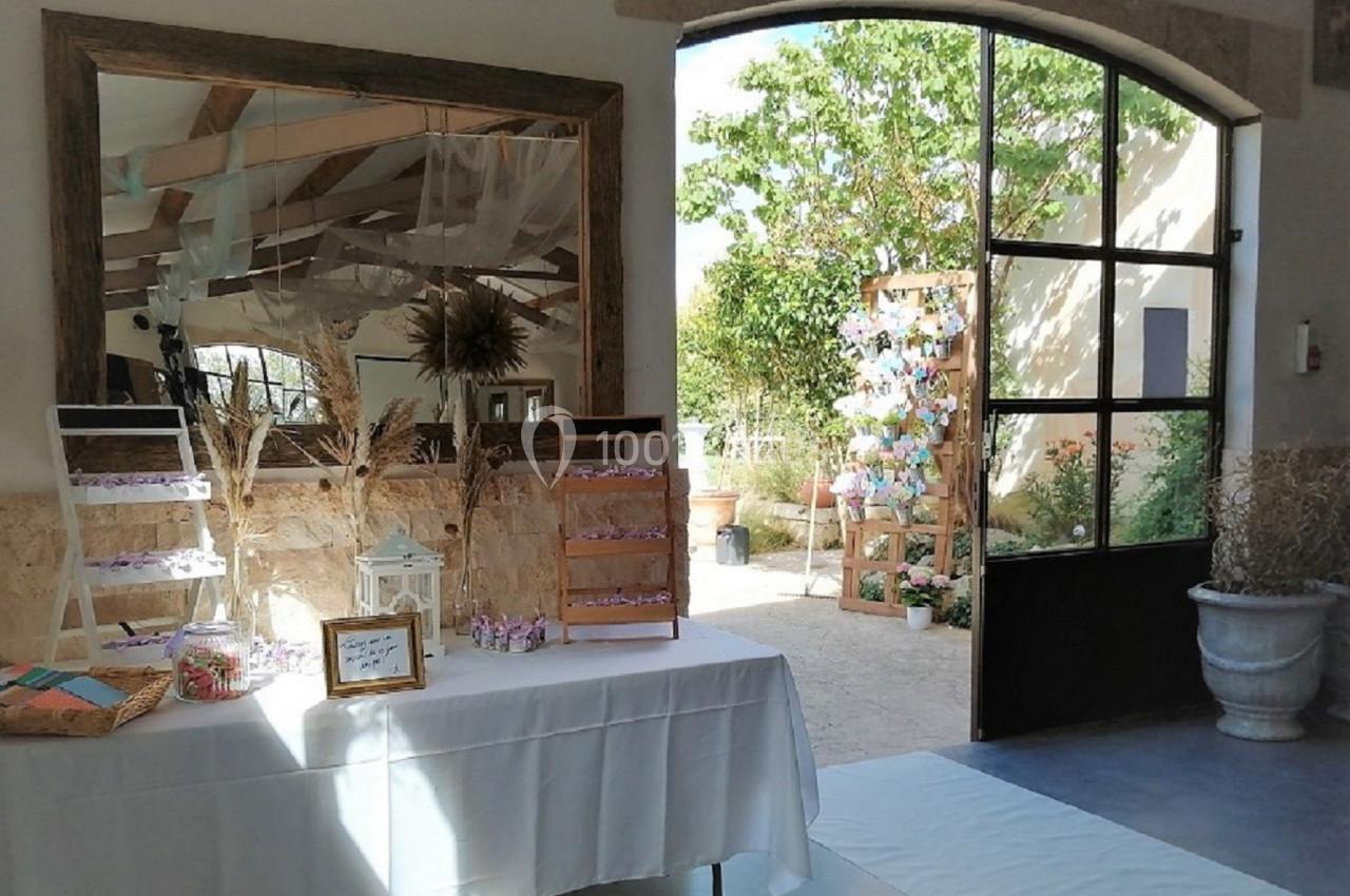 Table décorée avec des bonbonnières et des cadres, près d'une porte ouverte donnant sur un jardin ensoleillé.
