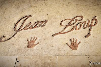 Texte ’Jean Loup’ écrit en calligraphie brune sur fond beige, accompagné de deux empreintes de mains.