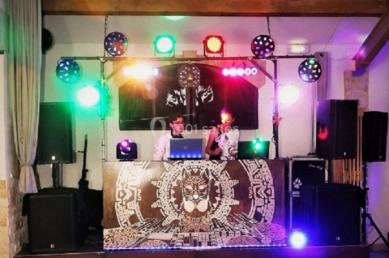 Deux DJ mixant sur une scène décorée, entourée de lumières colorées et d'équipements audio.