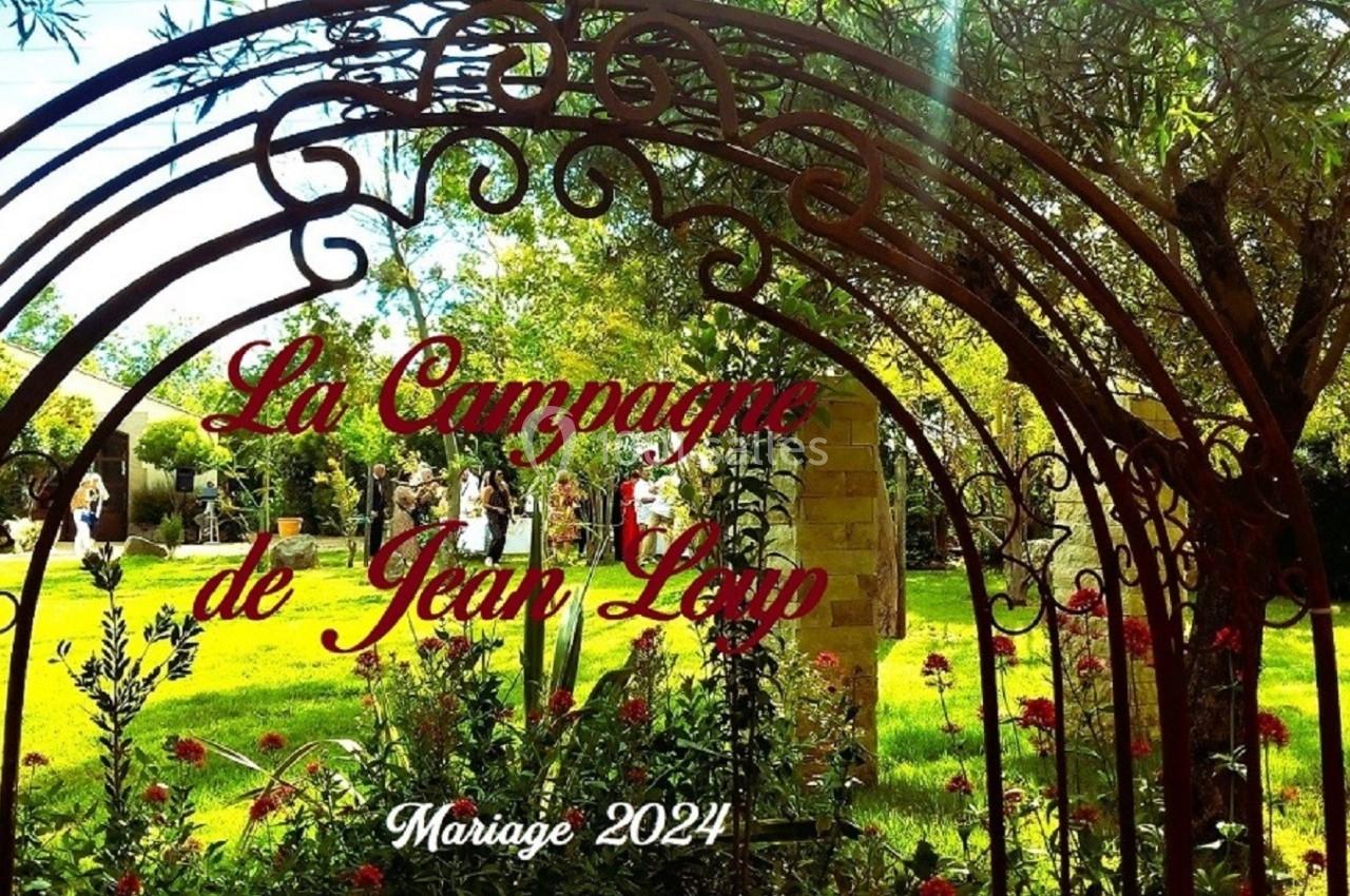 Arche en fer forgé ornée de végétation, donnant sur un jardin verdoyant sous une lumière ensoleillée.