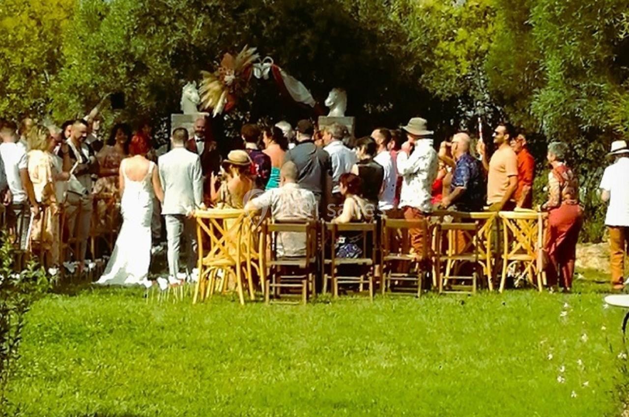 Un mariage en plein air avec des invités rassemblés autour d'une cérémonie dans un jardin verdoyant.