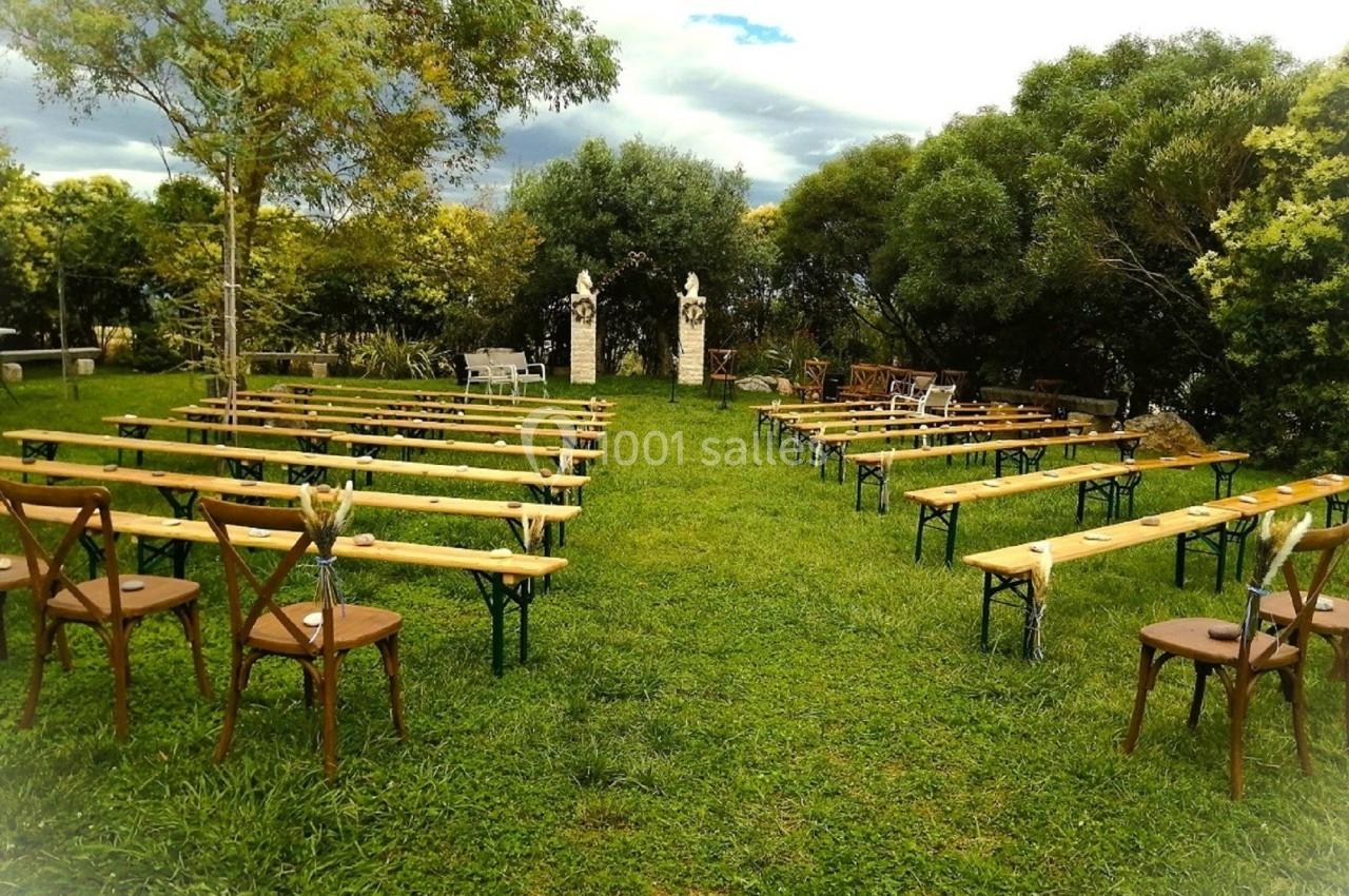 Chaises et bancs disposés en rangées sur une pelouse, formant une allée centrale, entourés d'arbres et de statues.