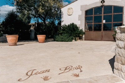 Texte ’Jean Loup’ écrit en calligraphie brune sur fond beige, accompagné de deux empreintes de mains.