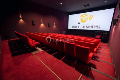 Espace intérieur spacieux avec moquette rouge, colonnes, éclairage tamisé et fauteuils disposés près des vitrines.