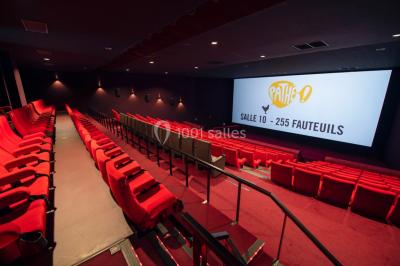 Espace intérieur spacieux avec moquette rouge, colonnes, éclairage tamisé et fauteuils disposés près des vitrines.