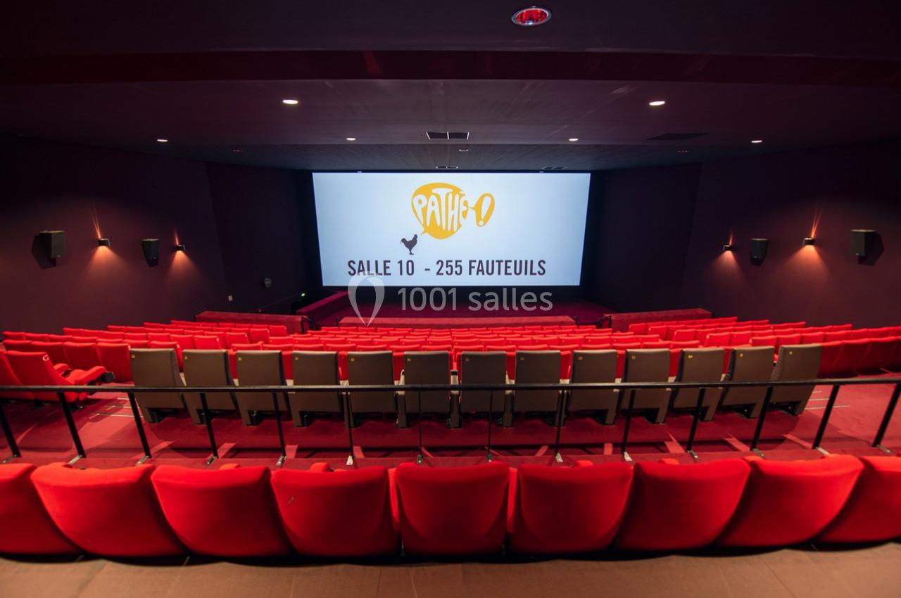 Salle de cinéma vide avec rangées de fauteuils rouges et écran affichant ’Salle 10 - 255 fauteuils’.