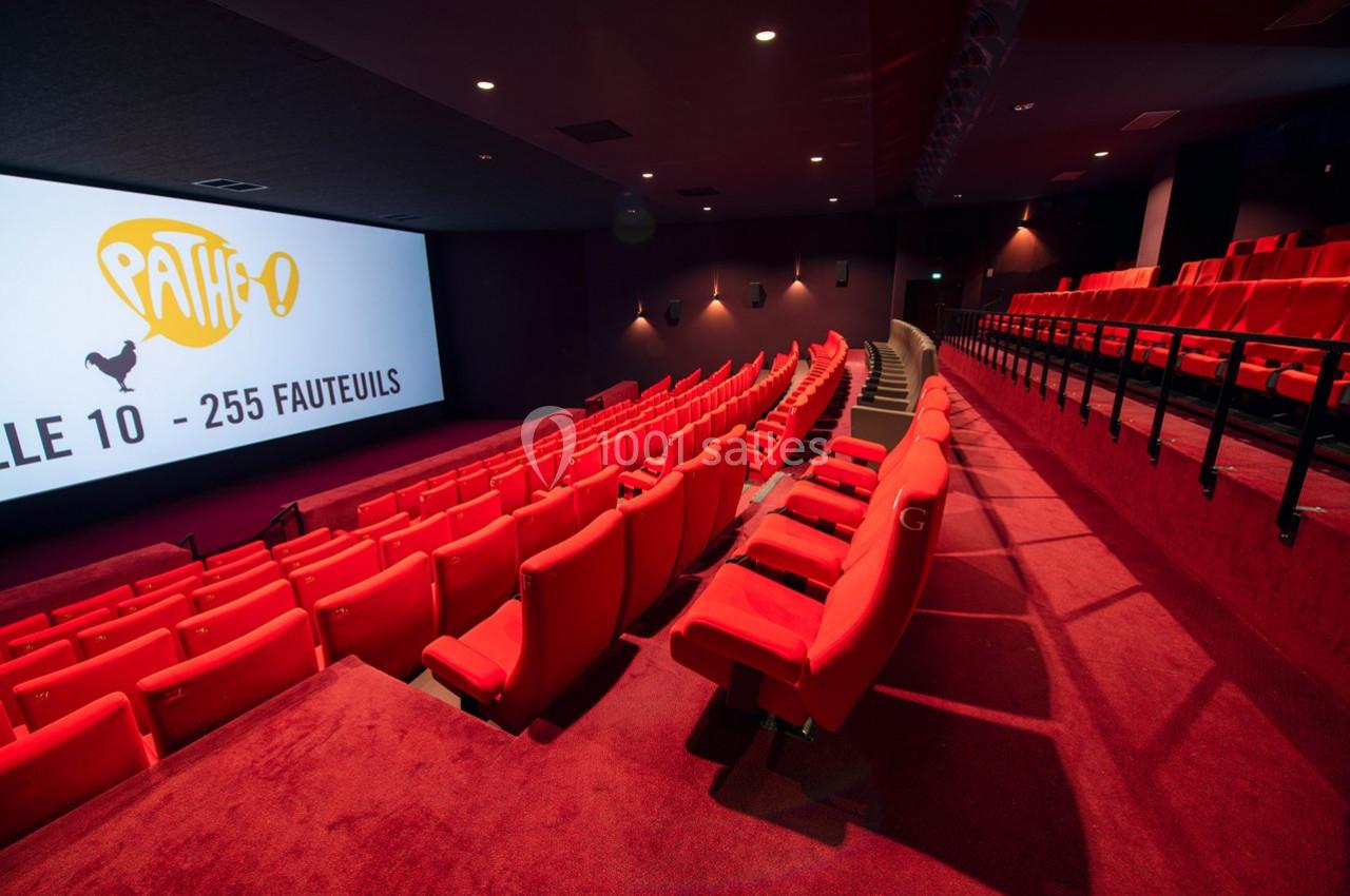Salle de cinéma moderne avec rangées de fauteuils rouges et écran affichant ’Salle 10 - 255 fauteuils’.