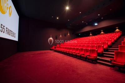 Espace intérieur spacieux avec moquette rouge, colonnes, éclairage tamisé et fauteuils disposés près des vitrines.