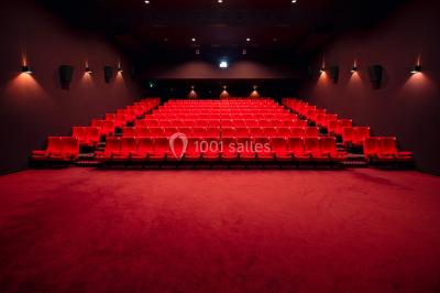 Espace intérieur spacieux avec moquette rouge, colonnes, éclairage tamisé et fauteuils disposés près des vitrines.