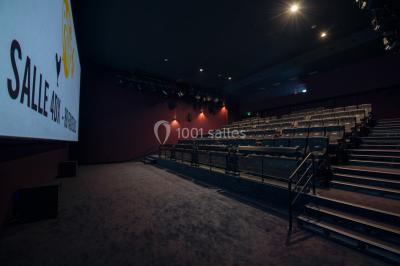 Espace intérieur spacieux avec moquette rouge, colonnes, éclairage tamisé et fauteuils disposés près des vitrines.