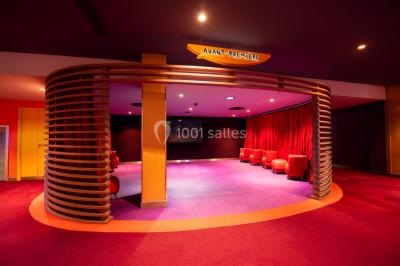 Espace intérieur spacieux avec moquette rouge, colonnes, éclairage tamisé et fauteuils disposés près des vitrines.