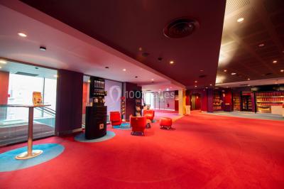Espace intérieur spacieux avec moquette rouge, colonnes, éclairage tamisé et fauteuils disposés près des vitrines.