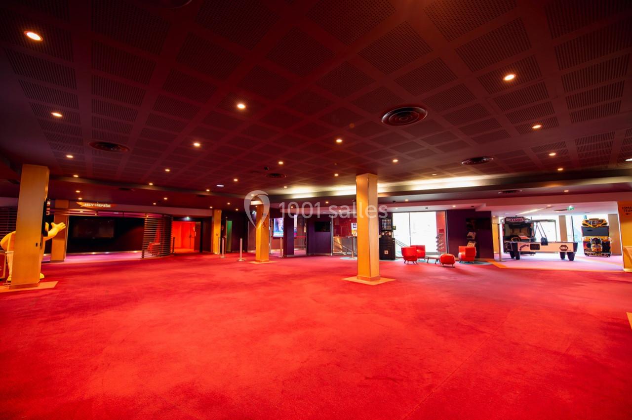 Espace intérieur spacieux avec moquette rouge, colonnes, éclairage tamisé et fauteuils disposés près des vitrines.