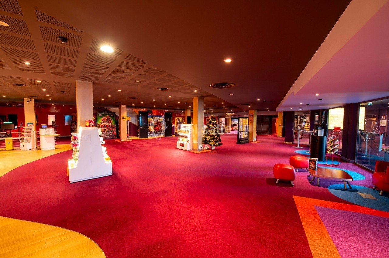 Espace intérieur lumineux avec moquette rouge, présentoirs blancs et décorations colorées dans un cadre moderne.