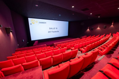 Rangée de fauteuils rouges numérotés dans une salle de cinéma sombre.