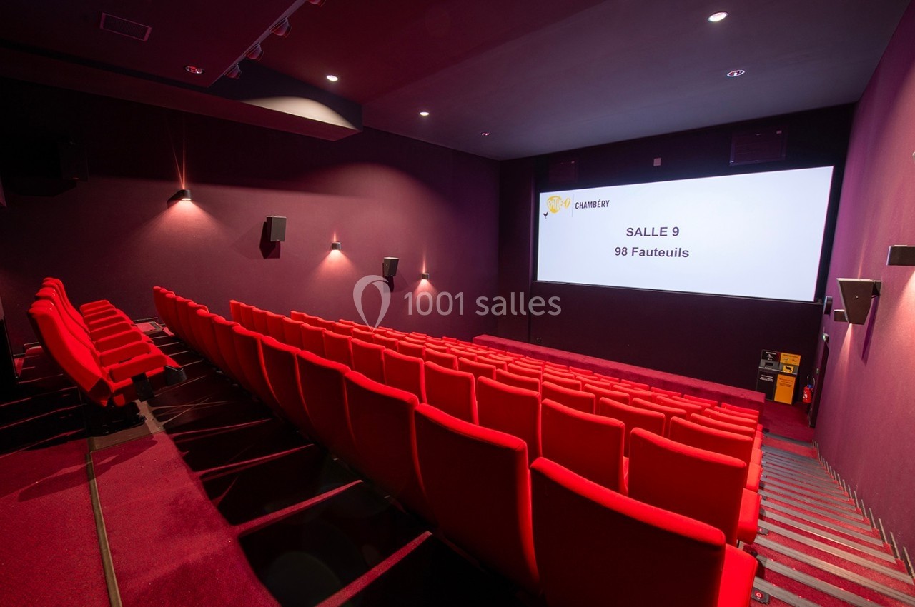 Salle de cinéma vide avec des rangées de fauteuils rouges et un écran affichant ’Salle 9, 98 fauteuils’.