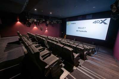Rangée de fauteuils rouges numérotés dans une salle de cinéma sombre.