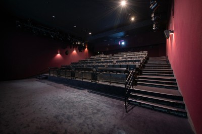 Rangée de fauteuils rouges numérotés dans une salle de cinéma sombre.