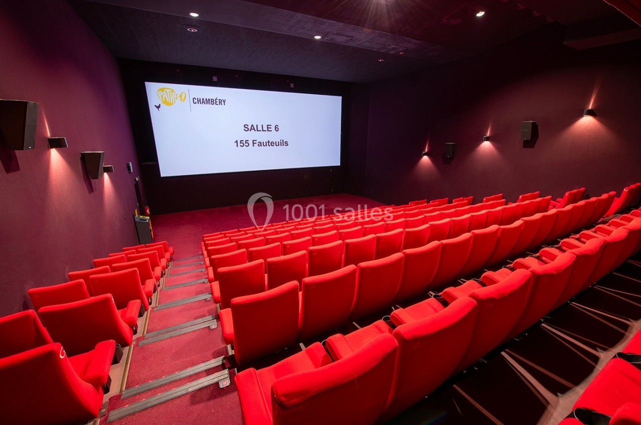 Salle de cinéma vide avec des rangées de fauteuils rouges et un écran affichant ’Salle 6, 155 fauteuils’.