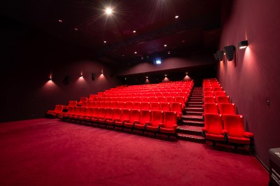 Rangée de fauteuils rouges numérotés dans une salle de cinéma sombre.