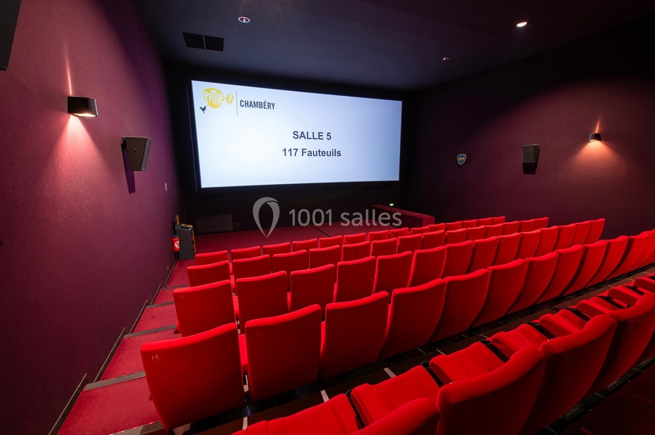 Salle de cinéma vide avec des rangées de fauteuils rouges et un écran affichant ’Salle 5 - 117 Fauteuils’.
